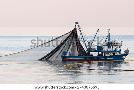 The fishing boat is casting its nets into the sea hoping for a good catch.