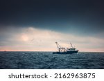 Fishing boat and fisherman in the sea, foggy morning over the water.