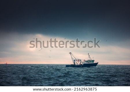 Fishing boat and fisherman in the sea, foggy morning over the water.