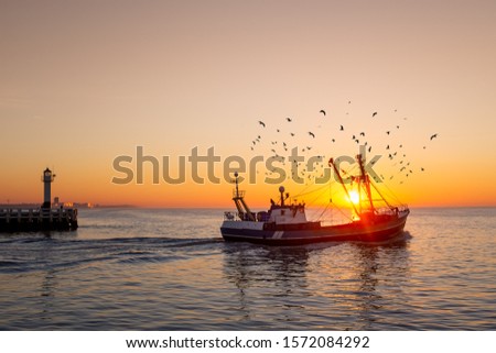 Fishing boat in front of the old wooden pier of Nieuwpoort at sunset