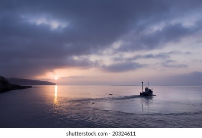 Fishing Boat Heading Out To Sea At Dawn, Beer, Devon, UK