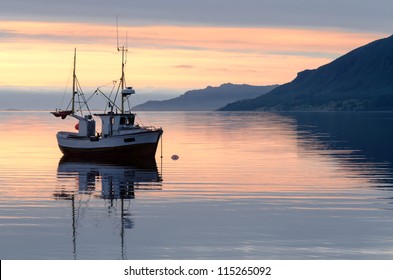 a fishing boat lies at sundown in the fjord