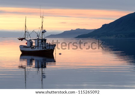 a fishing boat lies at sundown in the fjord