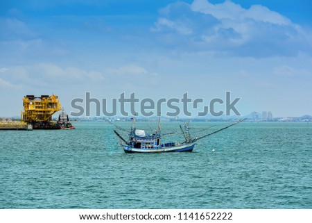 Fishing boat moored in the sea waiting and city background on sky blue