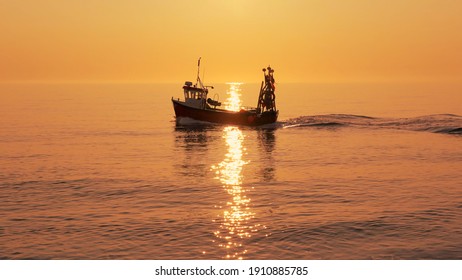 Fishing boat on a calm sea in early morning sunlight. Aldeburgh, Suffolk. UK - Powered by Shutterstock