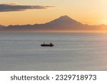 Fishing boat on Cook Inlet at sunset with Mount Redoubt in background