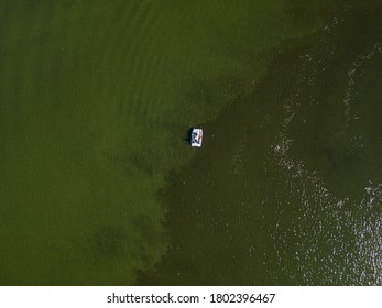 Fishing Boat On Green Water, Aerial Drone View. Algae Bloom In The River, Green Pattern On The Water.