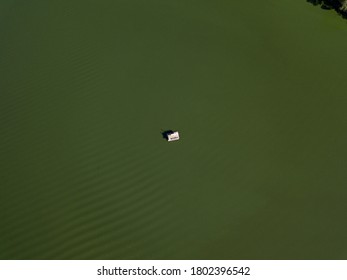 Fishing Boat On Green Water, Aerial Drone View. Algae Bloom In The River, Green Pattern On The Water.