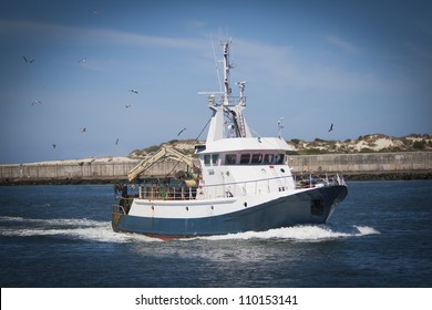 Fishing Boat Returning With Lots Of Seagulls Feeding At The Rear Of The Boat