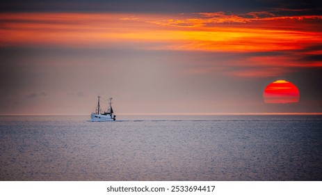 A fishing boat sailing on the calm sea during a vibrant sunset with a clear horizon. - Powered by Shutterstock