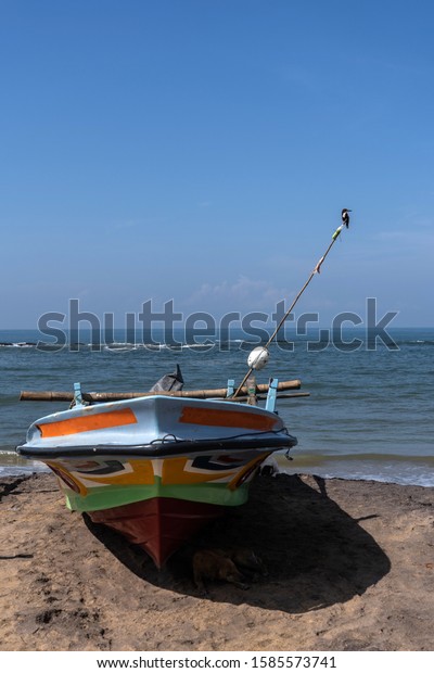 Fishing boat\
stands on the ocean beach. The Kingfisher bird sitting on a\
homemade fishing lighthouse on fishing\
boat.