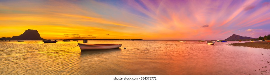 Fishing boat at sunset time. Le Morne Brabant on background. Mauritius. Panorama