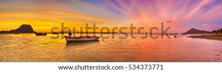 Fishing boat at sunset time. Le Morne Brabant on background. Mauritius. Panorama
