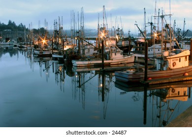 fishing boats dock during sunset with reflections in the water along the oregon coast