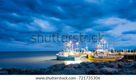 Fishing boats moored in Alma, Bay of Fundy, on the New Brunswick Atlantic coastline in Canada. Blue hour shot with dramatic clouds.
