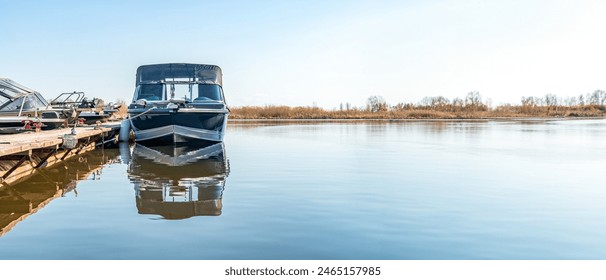 Fishing boats moored at wooden pontoon pier in early morning. Modern motorboats in small docks on calm river. Wide angle shot - Powered by Shutterstock