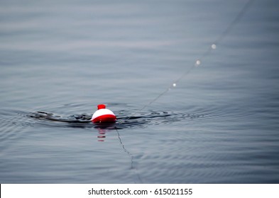 A fishing bobber shows some movement which means a fish is biting! don't let him get away! - Powered by Shutterstock