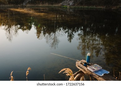 Fishing Day. Fishing Tackle - Fishing Spinning, Rod, Reel, Hooks, Fly, Bait, Lures In Box On Wooden Pier On Pond Background. Side View. Fishing For Pike, Perch. Recreation. Vintage Banner For Design.