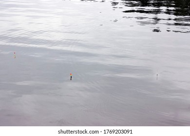 Fishing Float (bobber) Against The Background Of Water Close-up. Small Waves And Reflections Of The Sun On The Surface Of The Water. Fishing Concept And Place For Text.