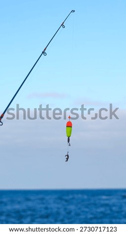 Fishing Float and Small Crab Hanging from Hook Over Calm Water — Recreational Catch Against Clear Sky