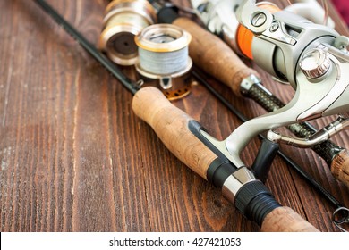 Fishing gear - fishing spinning, fishing line, hooks and lures on wooden background