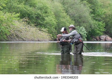 Fishing Guide With A Young Woman Fly Fishing For Trout In A Clear River