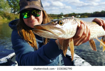 Fishing. Happy smiling fisher woman and trophy Pike, autumn colours and a beautiful lake - Powered by Shutterstock