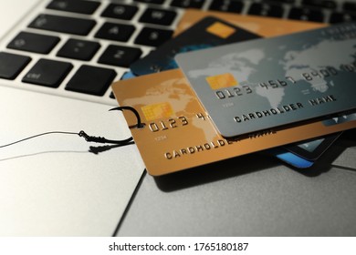 Fishing hook with credit cards on laptop, closeup. Cyber crime