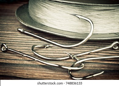 Fishing hooks. Fishing hooks on old wooden table. Four hooks for fishing and a skein fishing line - Powered by Shutterstock