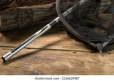 Fishing landing net on a wooden background. Fishing net and fishing rod near the tree. View from above.