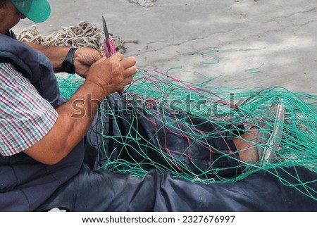 fishing nets being mended by hands, cris cross net netting repair
