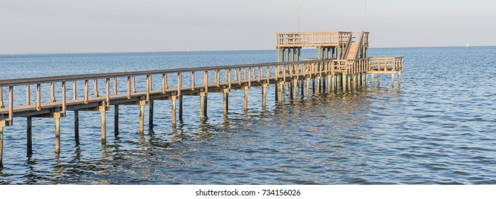 Fishing Piers Stretching Out Over Galveston Bay In Kemah, Texas, USA. Foot Pier For Saltwater Fishing Of Vacation Home/beach House Rental/bay Home In Lighthouse District Waterfront At Sunset. Panorama