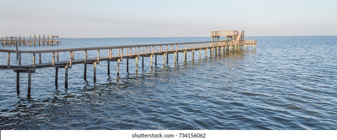 Fishing Piers Stretching Out Over Galveston Bay In Kemah, Texas, USA. Foot Pier For Saltwater Fishing Of Vacation Home/beach House Rental/bay Home In Lighthouse District Waterfront At Sunset. Panorama