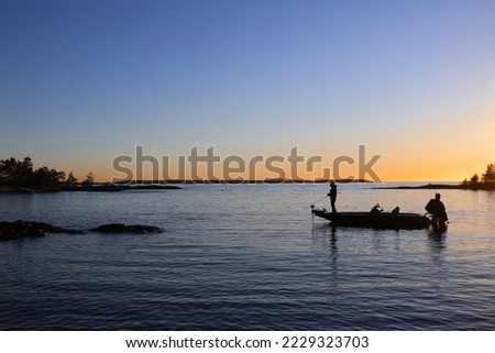Fishing for pike with high speed bass boat in the sunset. Fisherman casting in the last rays of light, on Lake Vänern. Scandinavia, Sweden.