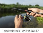 Fishing for pike, and perch from a lake or pond. Background wild nature. Fisherman with rod, spinning reel on the river bank. Wild nature. The concept of a rural getaway. Article about fishing day.