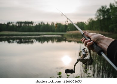 Fishing for pike, and perch from a lake or pond. Background wild nature. Fisherman with rod, spinning reel on the river bank. Wild nature. The concept of a rural getaway. Article about fishing day. - Powered by Shutterstock