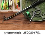 Fishing rod, baits, line, scissors, floats and net on wooden table, top view