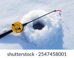  Fishing rod for ice fishing on snow near hole. Winter fishing on ice.