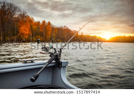 Fishing rod on the boat, sunset time. Beautiful autumn colors. A fishing rod is a long, flexible rod used by fishermen to catch fish. 