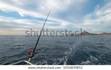 Fishing rod on charter fishing boat on the Sea of Cortes / Gulf of California viewing Lands End at Cabo San Lucas Baja Mexico BCS