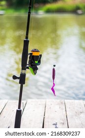 Fishing rod with reel and soft bait. Fishing for spinning and silicone bait. Opening by the water. Vertical spinning.