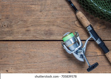 Fishing Rod And Spinning Reel With Line On Wooden Background With Free Space, Top View.