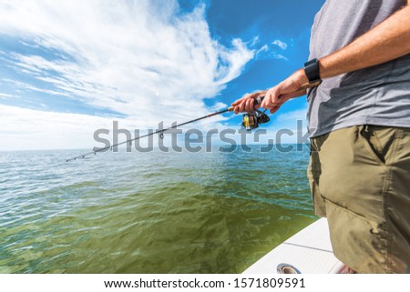 Fishing rod wheel man fishing from fisherman boat in Florida. Wearing smartwatch wearable technology for outdoor sport.
