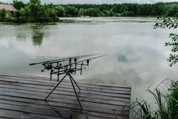 Fishing Rods For Carp Fishing With Signaling Devices On Holder. Rod Pod. Fishing For Pike, Perch, Carp On Background Of Lake And Nature.  Misty Morning. Wilderness Area. Fishing In Rainy Weather, Rain