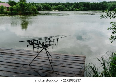 Fishing rods for carp fishing with signaling devices on holder. Rod pod. Fishing for pike, perch, carp on background of lake and nature.  Misty morning. Wilderness area. Fishing in rainy weather, rain