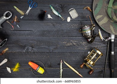 Fishing rods and reels, fishing tackle on black wooden background