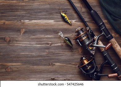 Fishing tackle - fishing spinning, hooks and lures on darken wooden background.Top view.