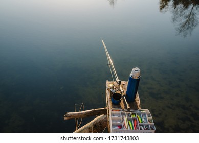 Fishing Tackle - Fishing Spinning, Rod, Reel, Hooks, Fly, Bait, Lures In Box On Wooden Pier On Pond Background. Top View. Fishing For Pike, Perch. Recreation. Fishing Day. Vintage Banner For Design.