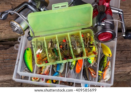 fishing tackles and fishing baits in box on vertical wooden board background. Design for outdoor sport business - templates, web, poster, card, advertisement.