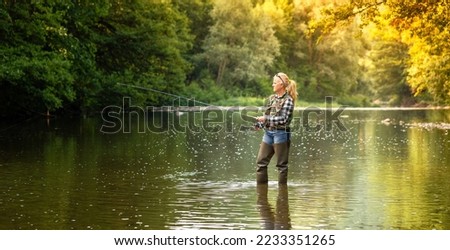 Fishing. Using a spinning reel, the woman stands in water and catches fish